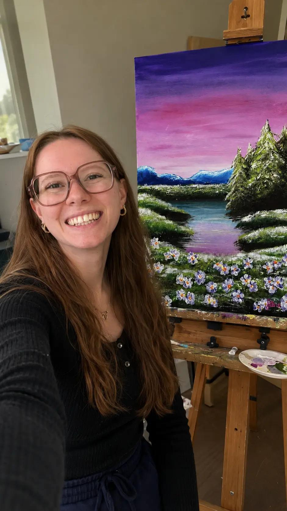 Selina Schweizer neben einem Landschaftsgemälde im Atelier